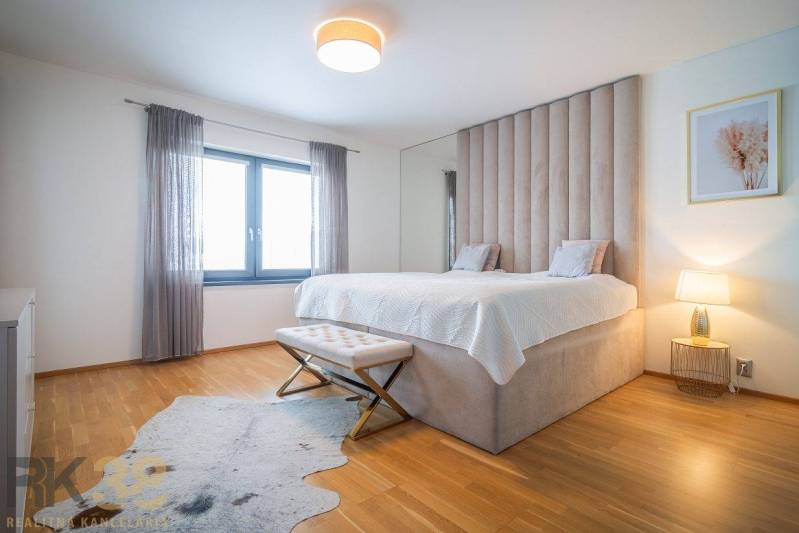 Bedroom in a family house with a bed, wooden decor flooring, and a fur rug.