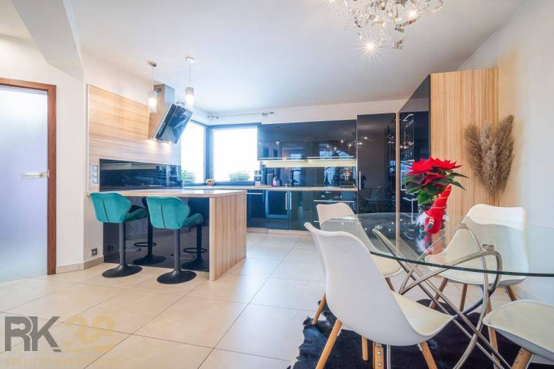 A bright kitchen with a dining table and bar stools in a family house.
