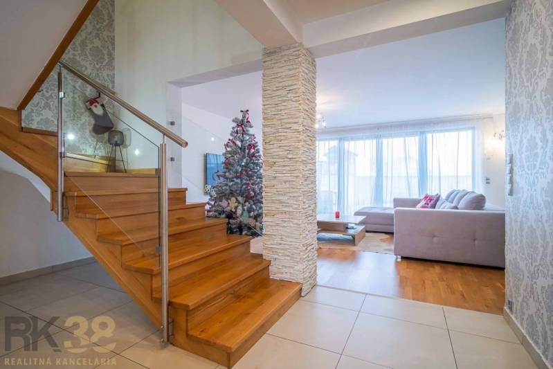 In the family house, you can see stairs, a Christmas tree, and a floor with a wooden decor.