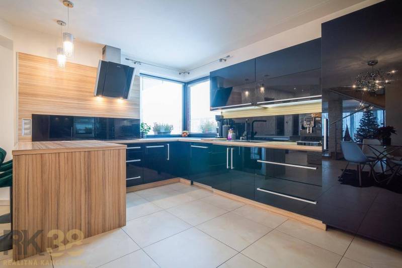 A kitchen in a family house with tiles, black glossy cabinets, and wood decor.