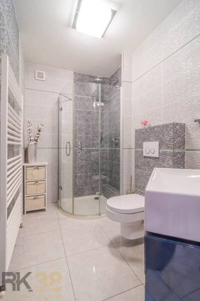 A bathroom in a family house with a shower, a toilet, and unique wall tiles.