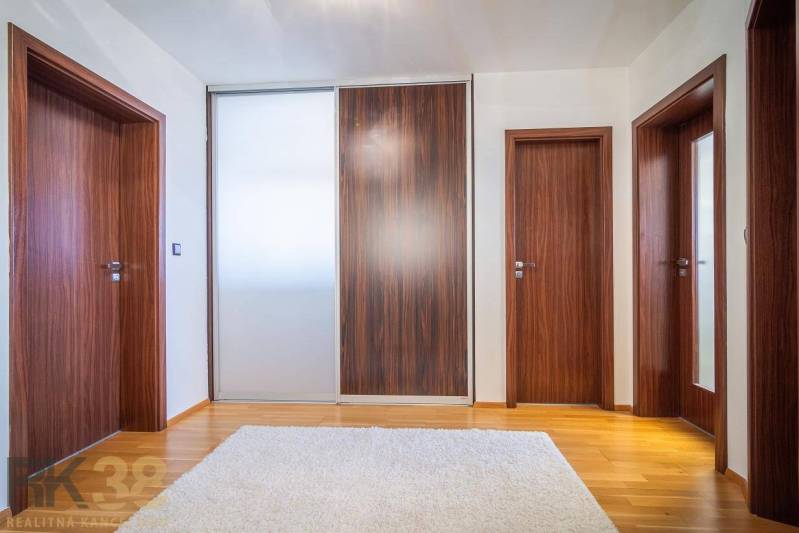 Interior of a family house with a wooden decor floor, a white carpet, and wooden doors.