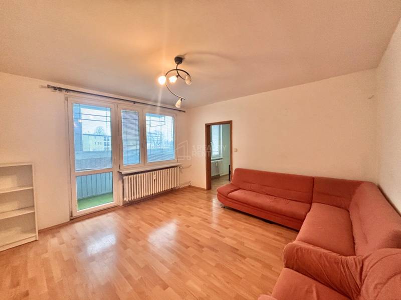 Living room with a sofa, wood-patterned floor, and a view of the balcony.