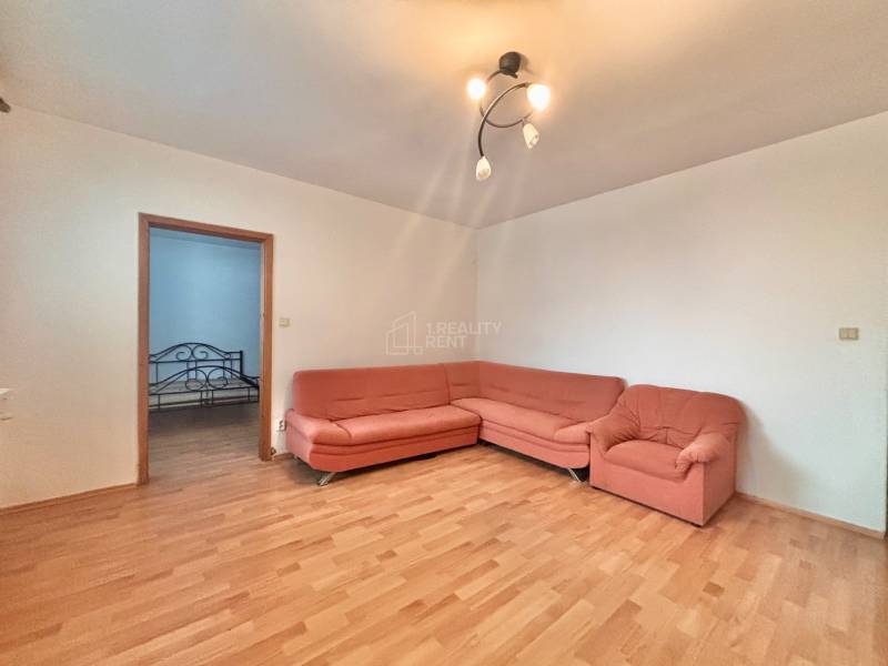 Living room in a 3-room apartment with a wooden decor floor and an orange sofa.