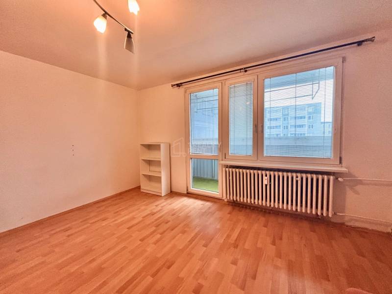 A room in a 3-room apartment with a wooden decor floor and a large window.
