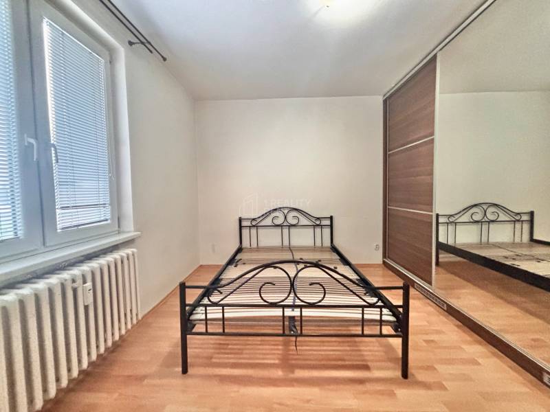 Bedroom with a metal bed, built-in wardrobe, and wooden decor flooring in a 3-room apartment.