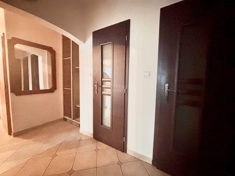Hallway in a 3-room apartment with tiles, a mirror, and dark doors.