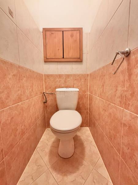 A bathroom with tiles and a wooden cabinet in a 3-room apartment.