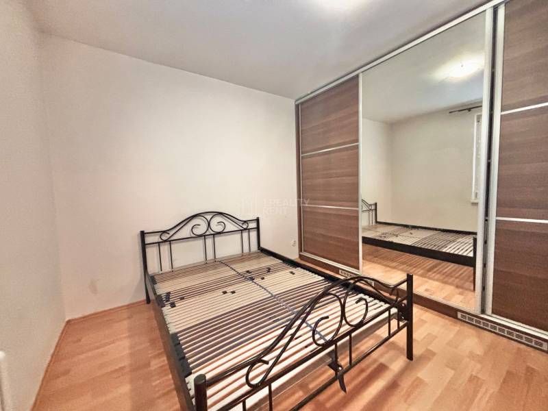 Bedroom in a 3-room apartment with a metal bed and a wardrobe, floor with wooden decor.