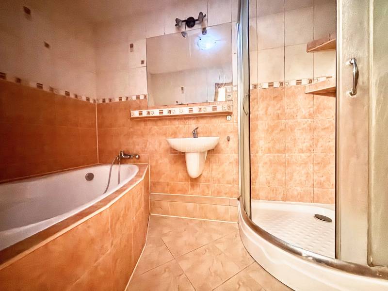 A bathroom in a 3-room apartment with a bathtub, shower, and ceramic tiles.