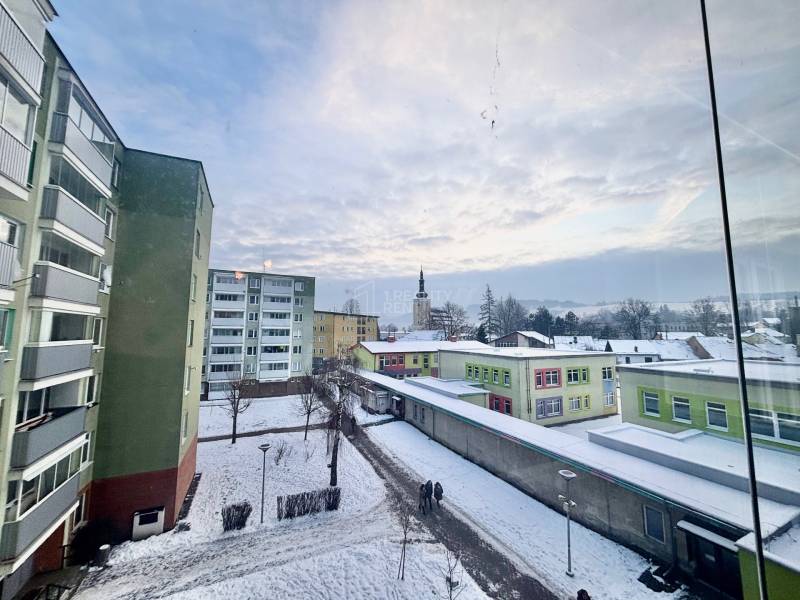 Snow-covered street Centrum in Turzovka with apartment buildings and a distant tower.