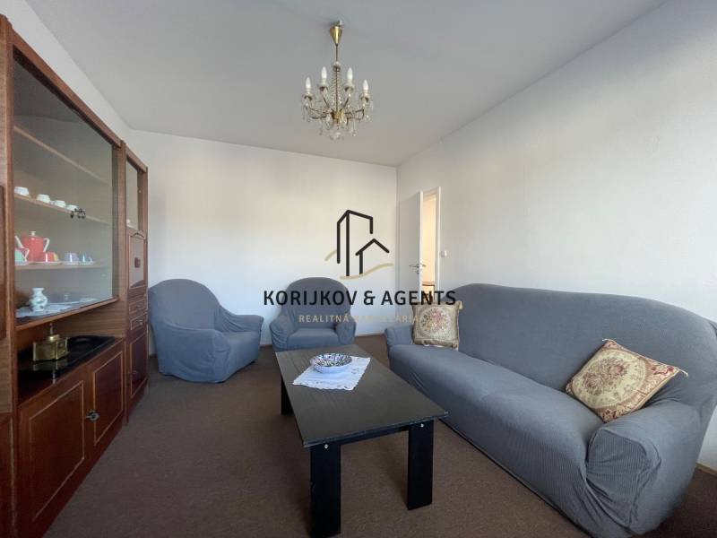 Living room in a 3-room apartment with a comfortable sofa, armchairs, and a display cabinet.