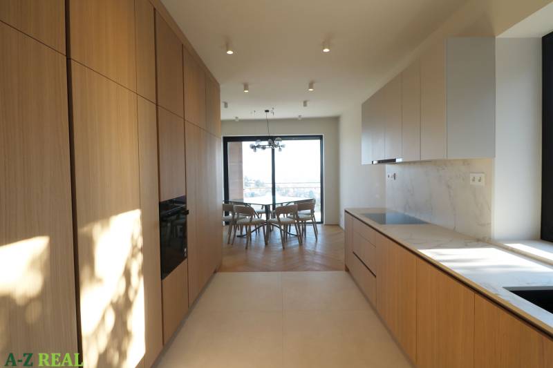 A kitchen in a 4-room apartment with a wood-patterned floor and a light-colored kitchen unit.