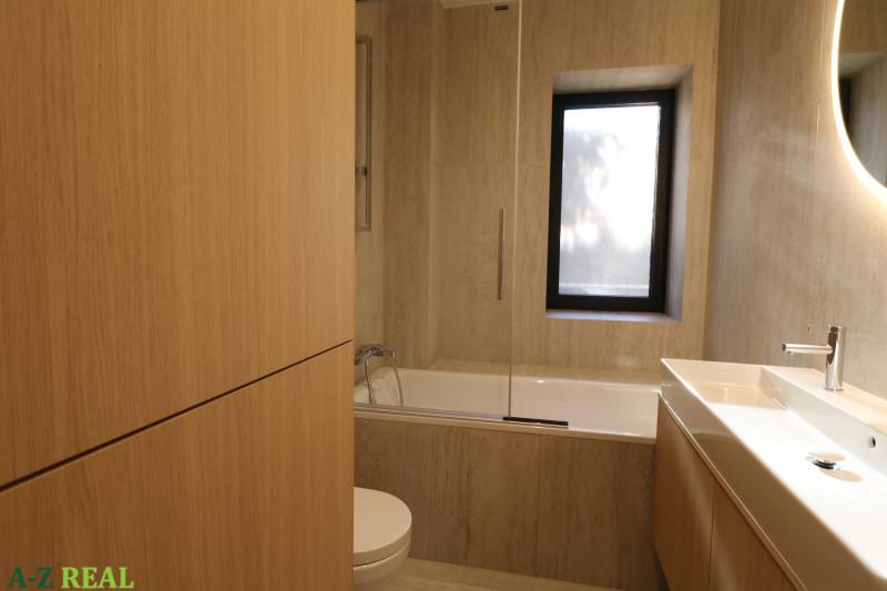 A bathroom with a bathtub and a sink in a 4-room apartment with a wooden decor.