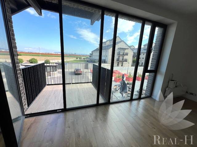 Glass doors leading to a balcony with a view in a 2-room apartment and a floor with a wooden decor.