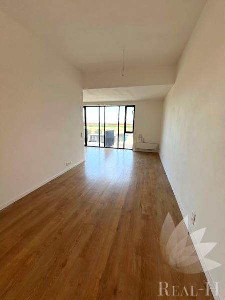 Living room with wood-patterned flooring in a 2-room apartment, glass wall.