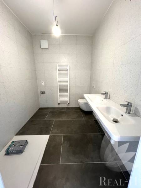 Bathroom with large-format tiles, sink, toilet, and ladder radiator in a 2-room apartment.