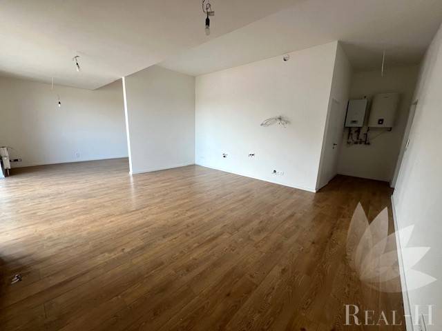 Interior of a 2-room apartment with wood-patterned flooring, white walls, open space.