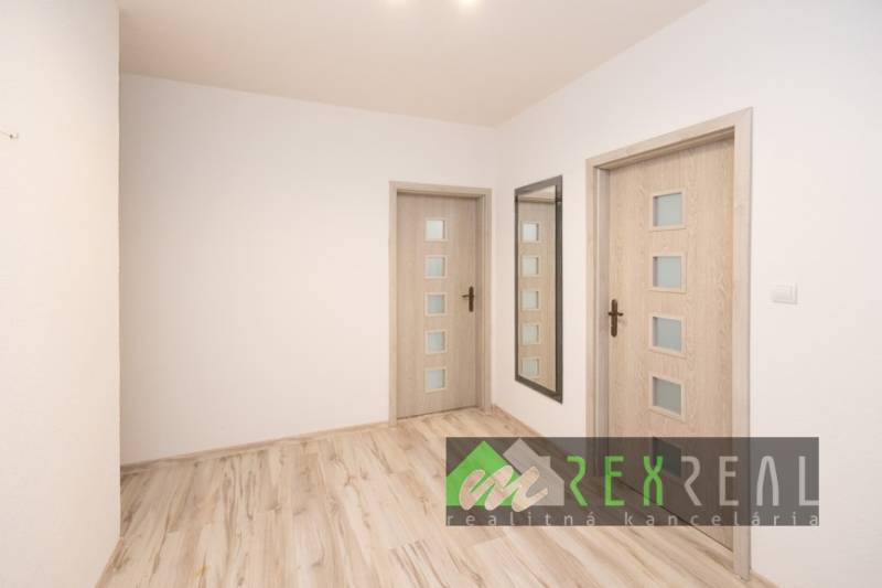 A hallway in a 3-room apartment with a wooden decor floor and a mirror.