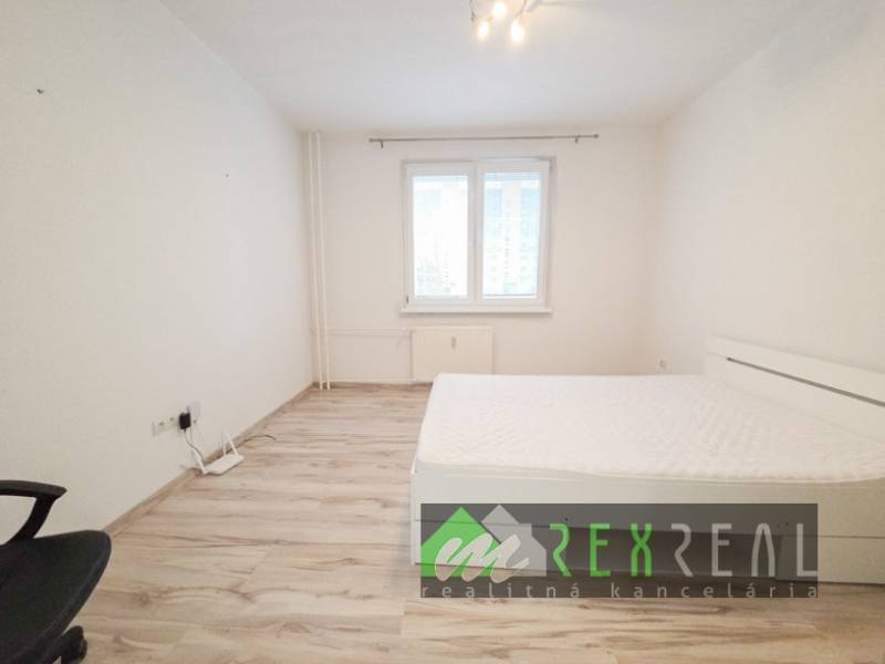 A bright bedroom in a 3-room apartment with a wooden decor floor and simple furniture.