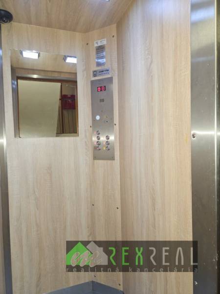 An elevator with a wooden decor floor and a mirror in a 3-room apartment.
