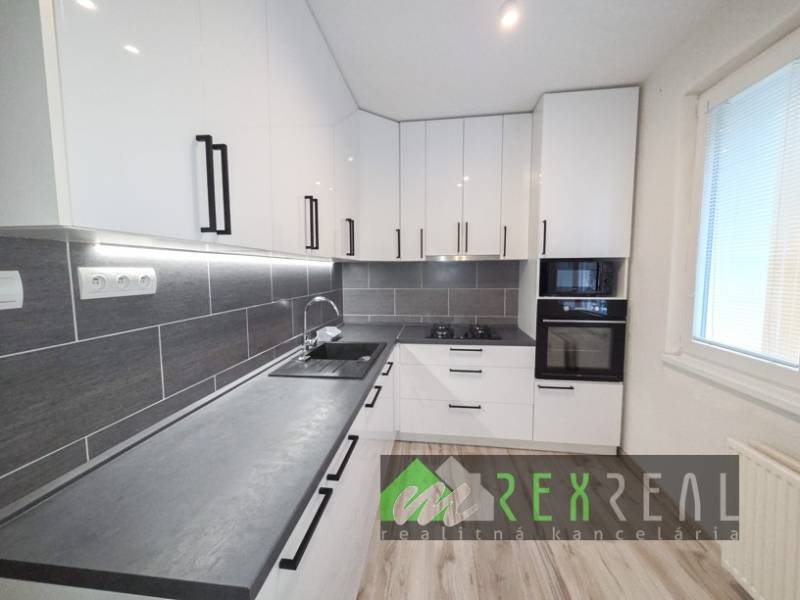 A kitchen in a 3-room apartment with white cabinets and a wooden decor floor.