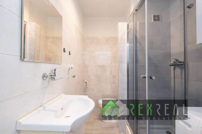 Bathroom in a 3-room apartment with a shower, sink, and light tiles.