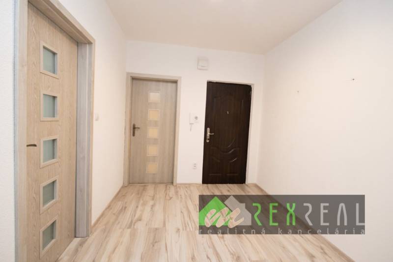 Interior of a 3-room apartment with wood-patterned flooring and white walls.