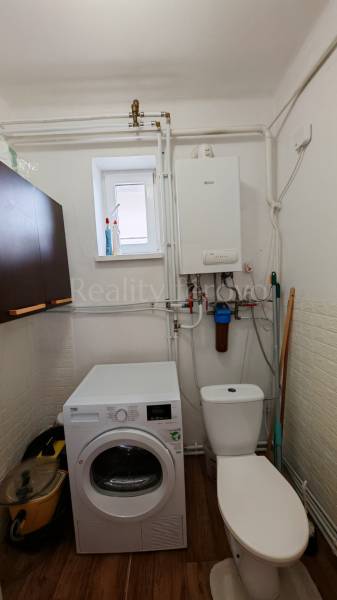 Bathroom in a family house with a washing machine and a boiler, floor with wood decor.