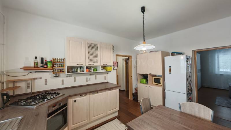 A kitchen in a family house with white cabinets and a wood-patterned floor.