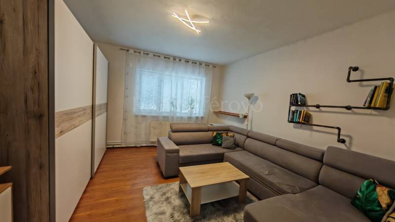 Living room in a family house with a sofa, a bookshelf, and a wooden decor floor.