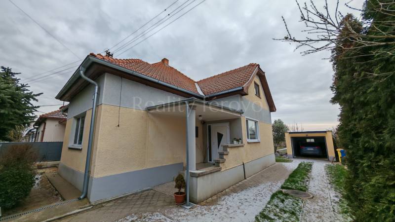 A family house in Trnovec nad Váhom with a landscaped garden and a garage on a quiet street.