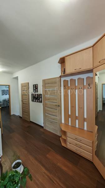 A hallway in a family house with a wooden decor floor, coat racks, and a small bookshelf.