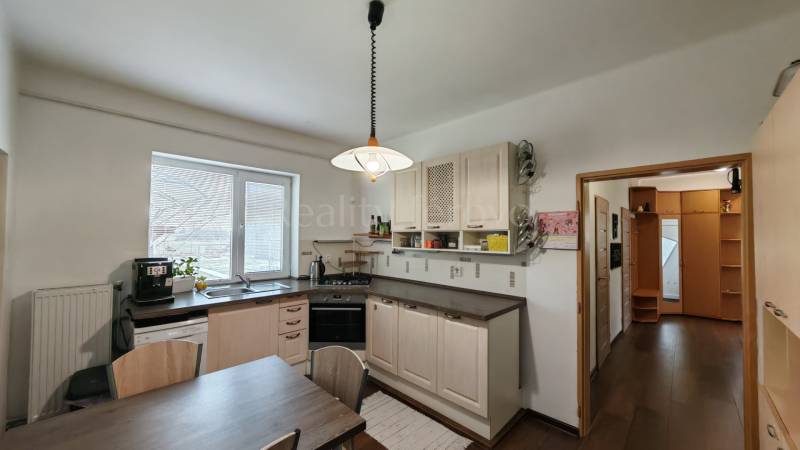 A kitchen in a family house with a light, sink, dishwasher, and table, floor with a wooden decor.