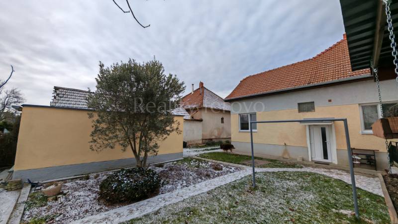 A snow-covered garden with a family house in Trnovec nad Váhom, surrounded by trees and lawn.