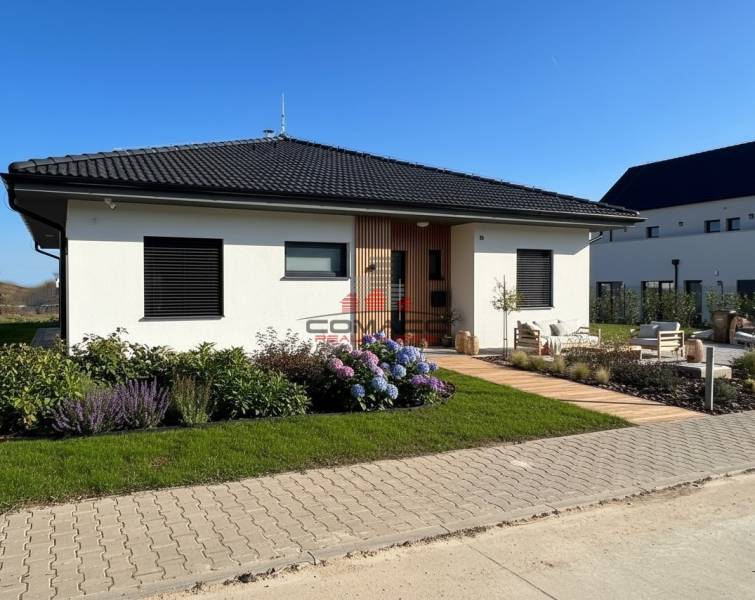 A family house in Madunice on Madunice street with colorful flowers and a paved walkway.