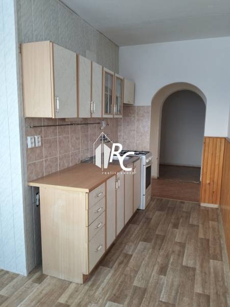 A kitchen in a 2-room apartment with a wood-patterned floor and an arched doorway.