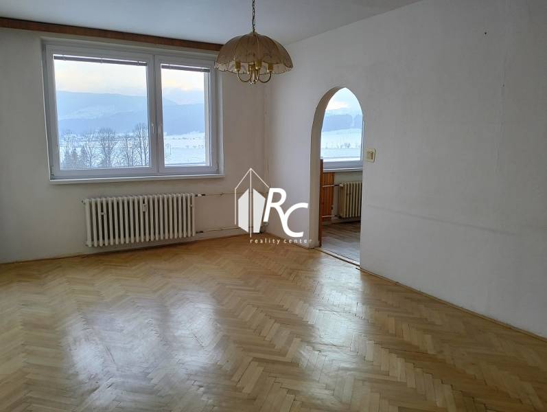 A spacious room with a wooden decor floor and large windows in a 2-room apartment.
