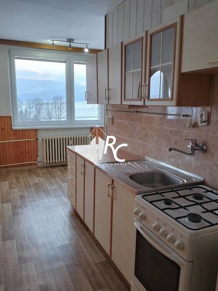 A kitchen in a 2-room apartment with a wooden decor floor and a view of nature.