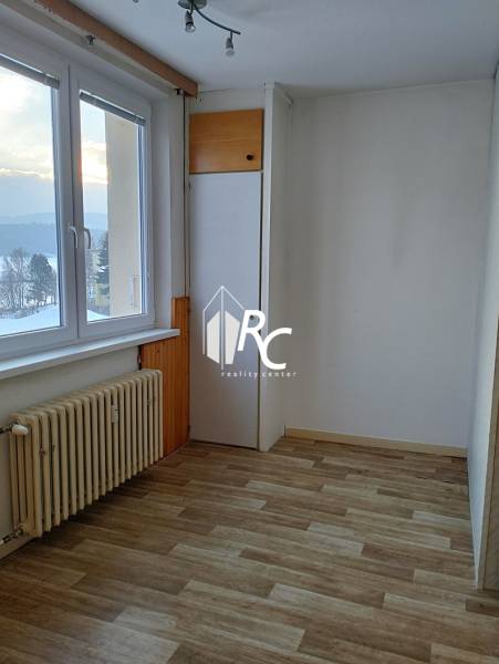 A bright room in a 2-room apartment with a wooden decor floor and a radiator.