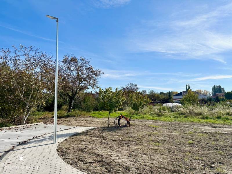 A residential plot in Malinovo on Malinovo Street with a concrete sidewalk and trees.