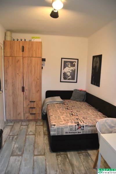 A room in a 3-room apartment with a bed, a wardrobe, and a floor with a wooden decor.