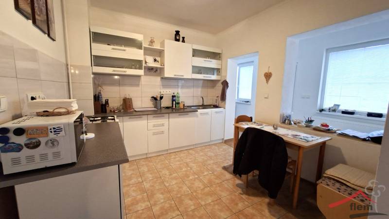 A kitchen in a family house with white cabinets, a table, and tiles.