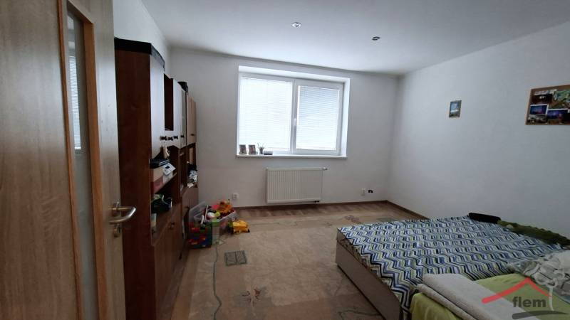 A room in a family house with a bed, furniture, and a wooden decor floor.