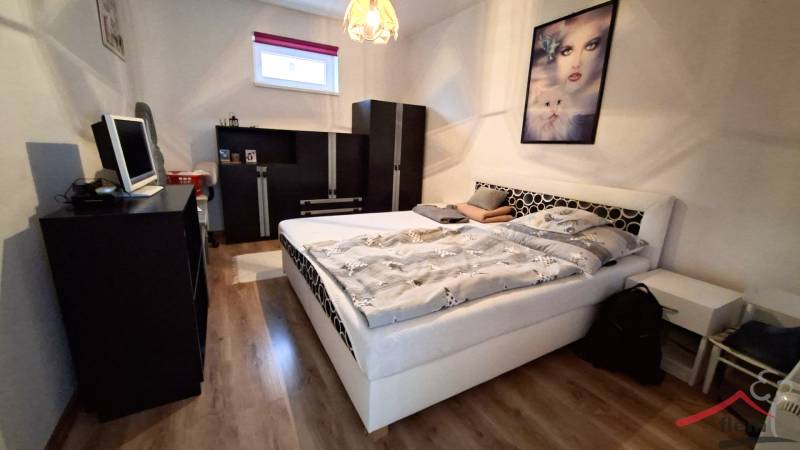 Bedroom in a family house with wood-patterned flooring, a bed, and black furniture.