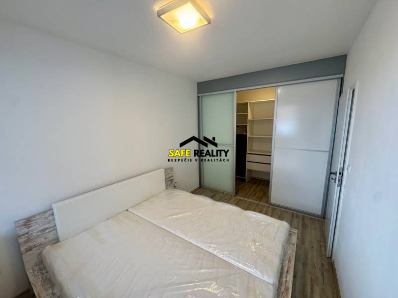 Bedroom with a double bed, built-in wardrobe, and wooden decor flooring in a 2-room apartment.