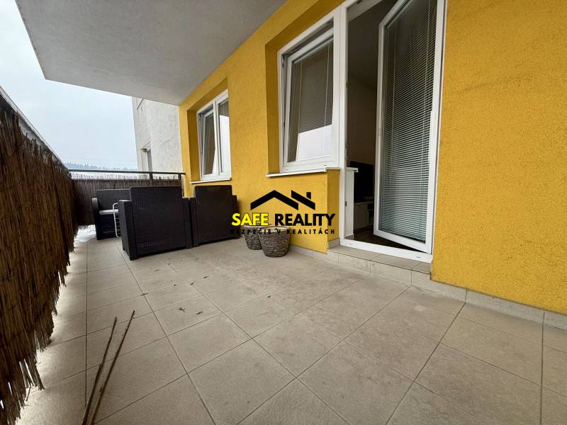 A balcony of a 2-room apartment in Žilina with a tiled floor and garden furniture.