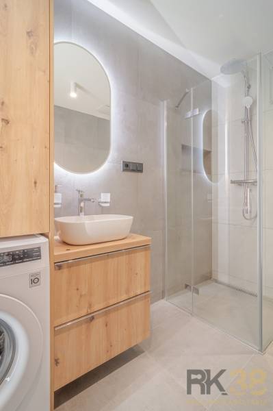 Bathroom in a 2-room apartment with a sink, shower, and washing machine.