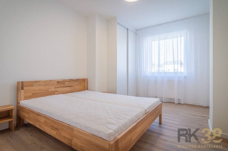 Bright bedroom with a wooden bed and a window in a 2-room apartment.