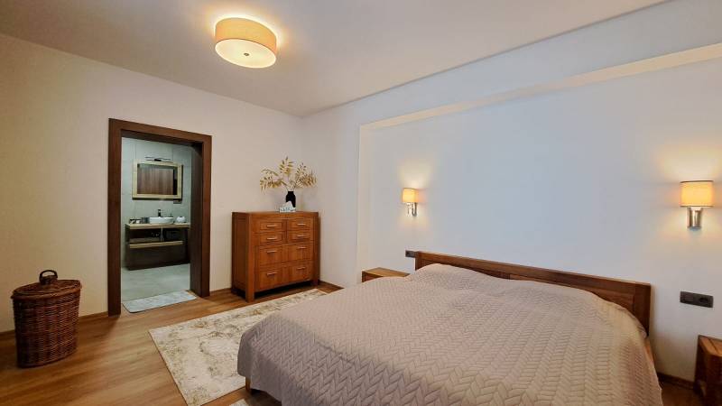 A bedroom in a two-room apartment with a bed, wooden furniture, and a floor with a wooden decor.